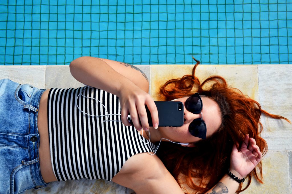 girl by pool looking at social media