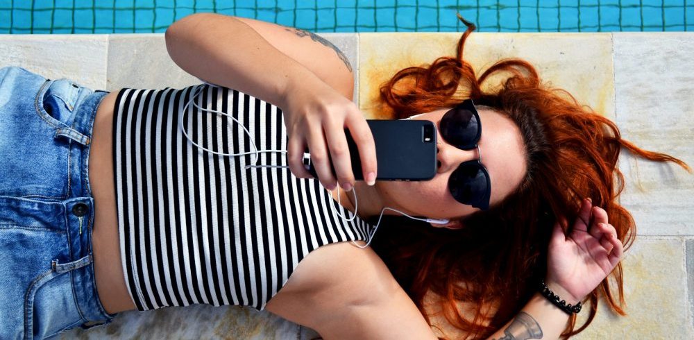 girl by pool looking at social media