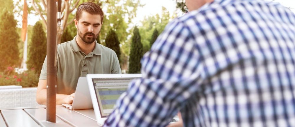 two men outside on laptops using linkedin