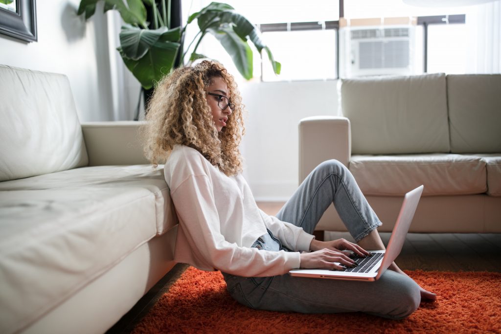 woman using laptop while sitting on floor