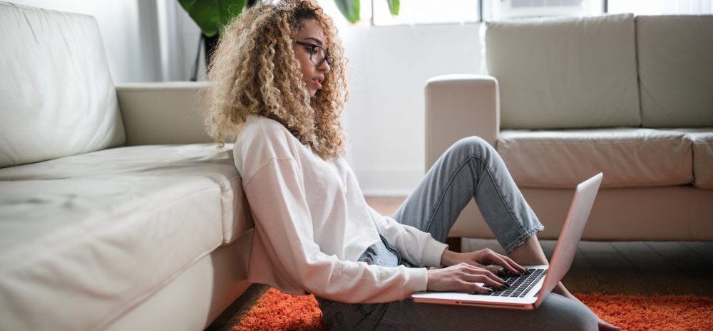 woman using laptop while sitting on floor