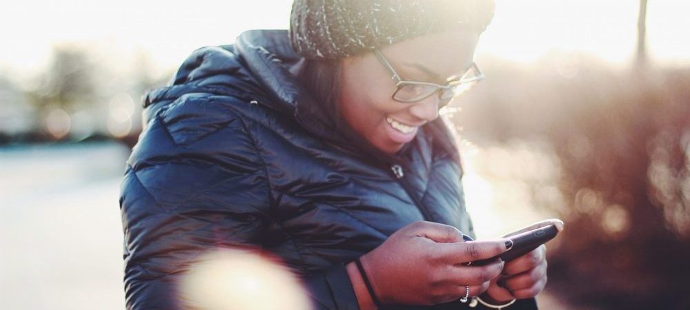 woman in hat looking at cell phone