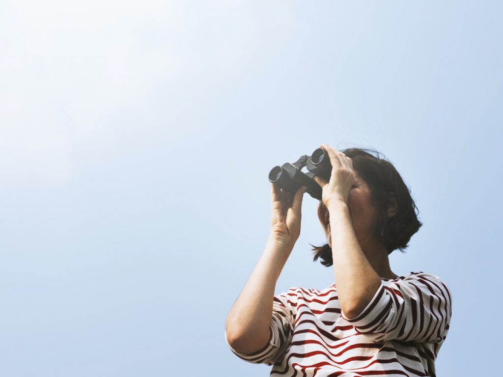 woman searching with binoculars outside