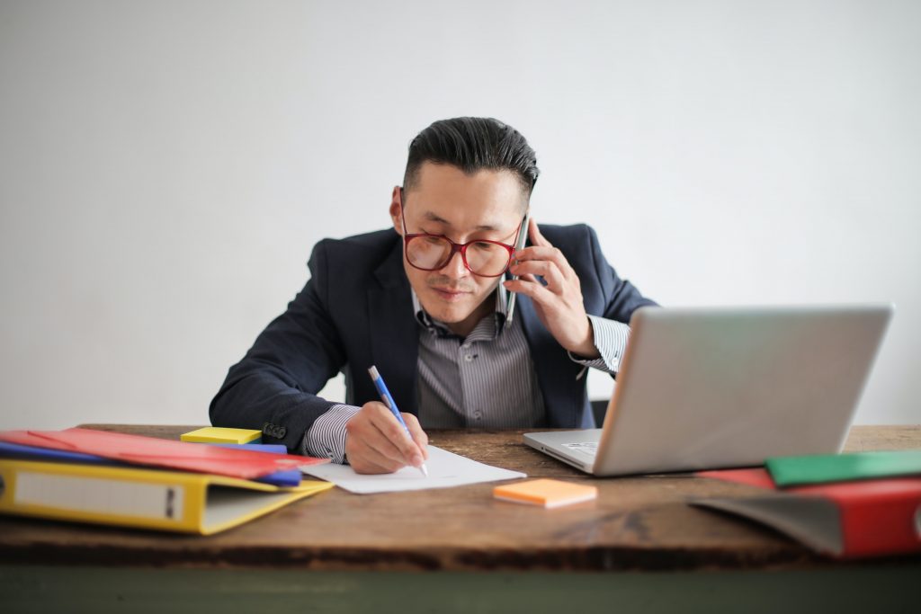 man on phone and writing something down with a pencil