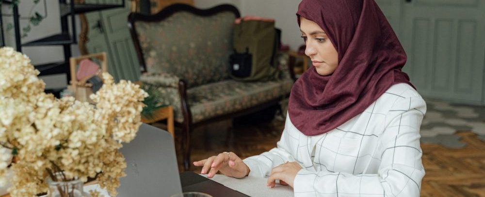 woman sitting at a table on laptop computer