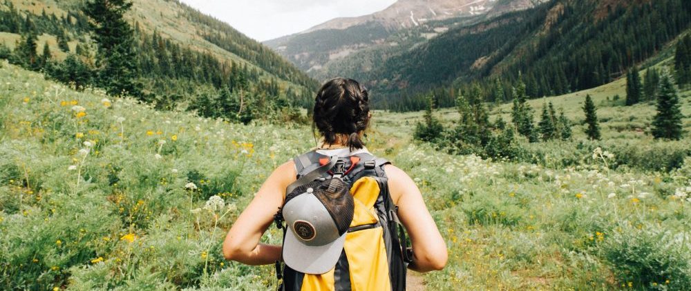 person hiking down an outdoor path with a hat and backpack