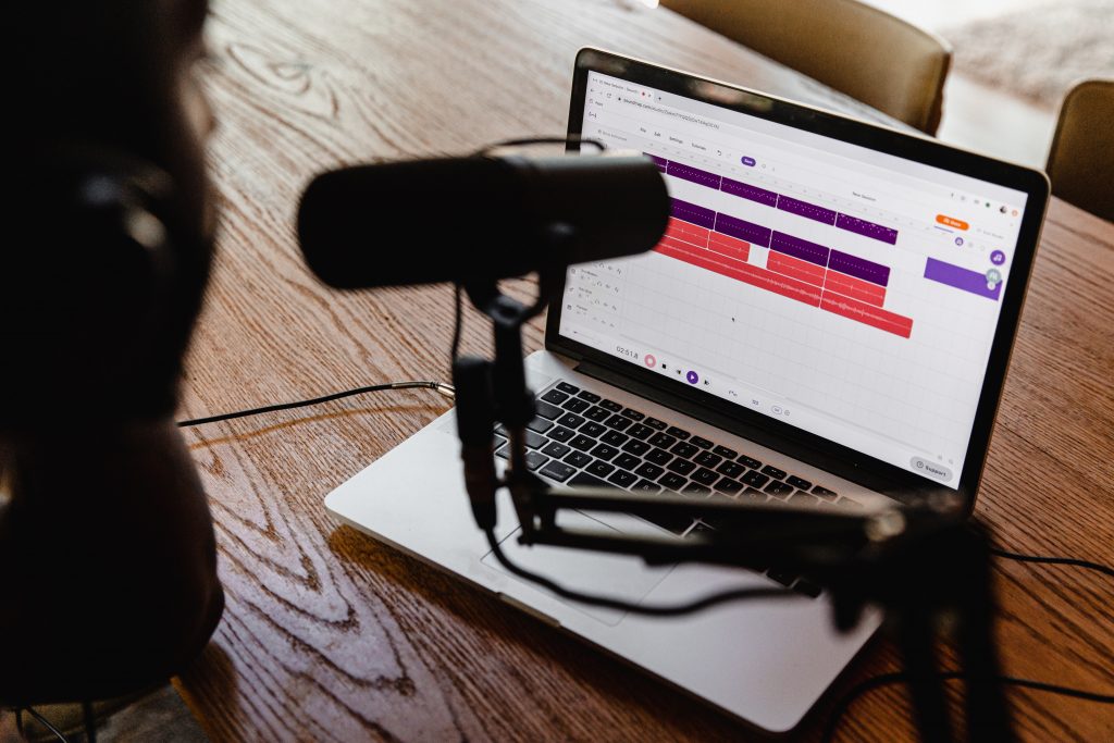 person recording a podcast with a microphone and laptop