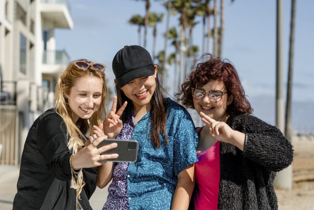 Teen girls taking selfie, enjoying summer together in Venice Beach, Los Angeles