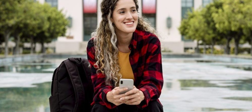 girl sitting outside on her smartphone